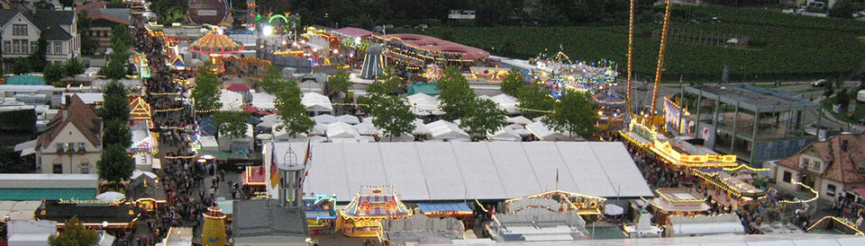 Blick auf den Wurstmarkt im Jahr 2010 aus einer Gondel des Riesenrads heraus. Im Hintergrund ist neben dem Turm-Fahrgeschäft das Dürkheimer Riesenfass zu erkennen.