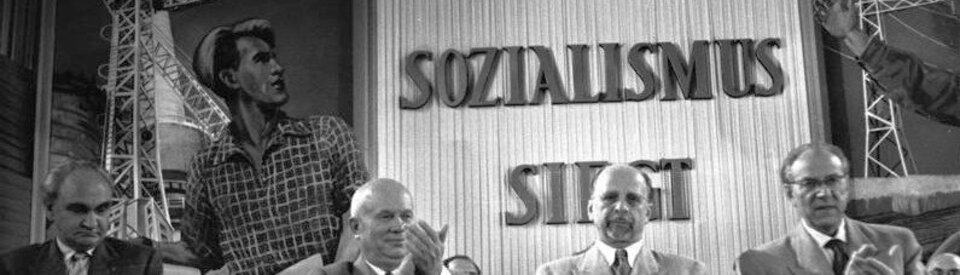 SED-Parteitag, vlnr: Nikita Sergejewitsch Chruschtschow, Walter Ulbricht, Otto Grotewohl. Im Hintergrund Parole "Der Sozialismus siegt".